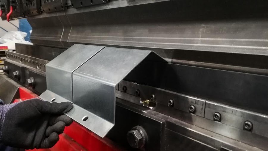 Aluminum repair in Columbus, Ohio: fabricator holding a formed metal transition piece at the press brake